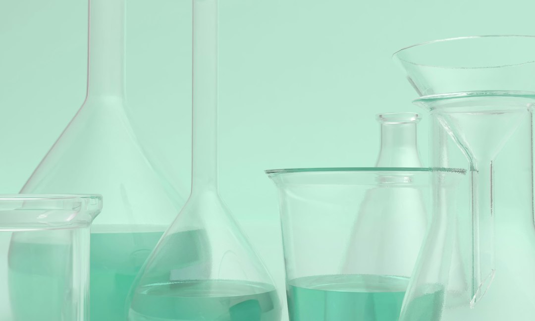 Clear laboratory glassware with pale teal liquid representing professional chemical peel formulations