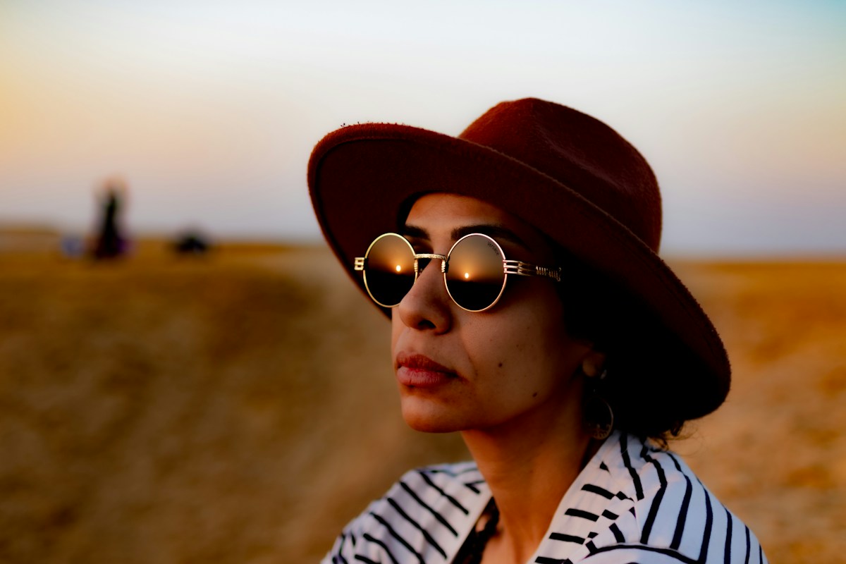 Woman outdoors wearing a wide-brimmed hat and round sunglasses