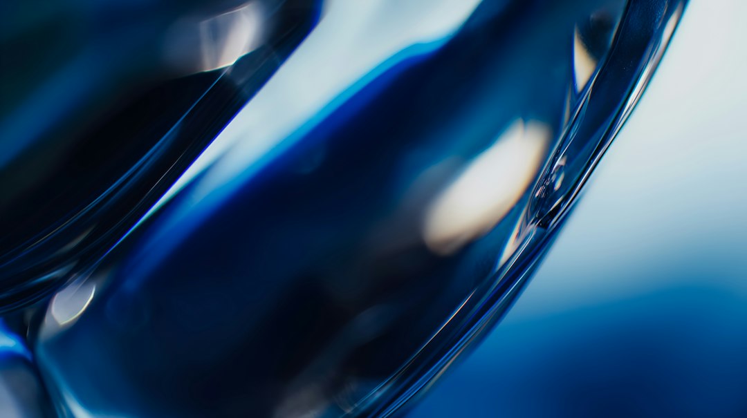 Abstract translucent teal and silver glass curves, used as an illustrative image for facial thread vein laser recovery